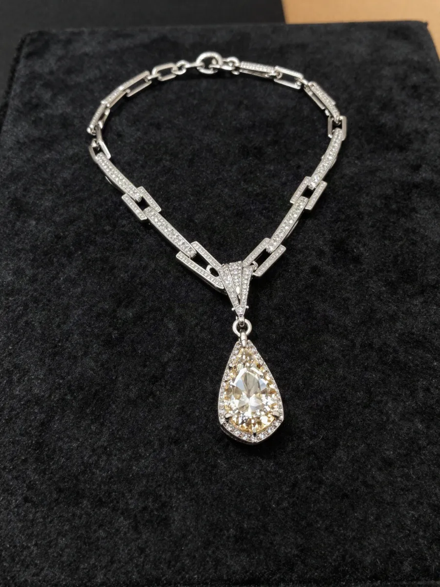 A deco diamond necklace ending in a pear drop, on black velvet