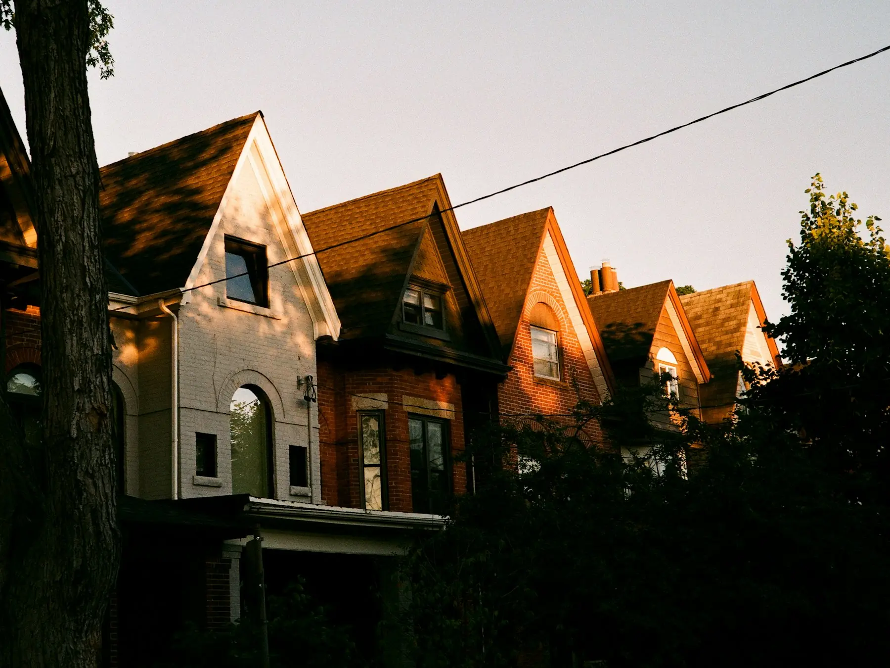 A row of brick houses with steep gables in warm evening light