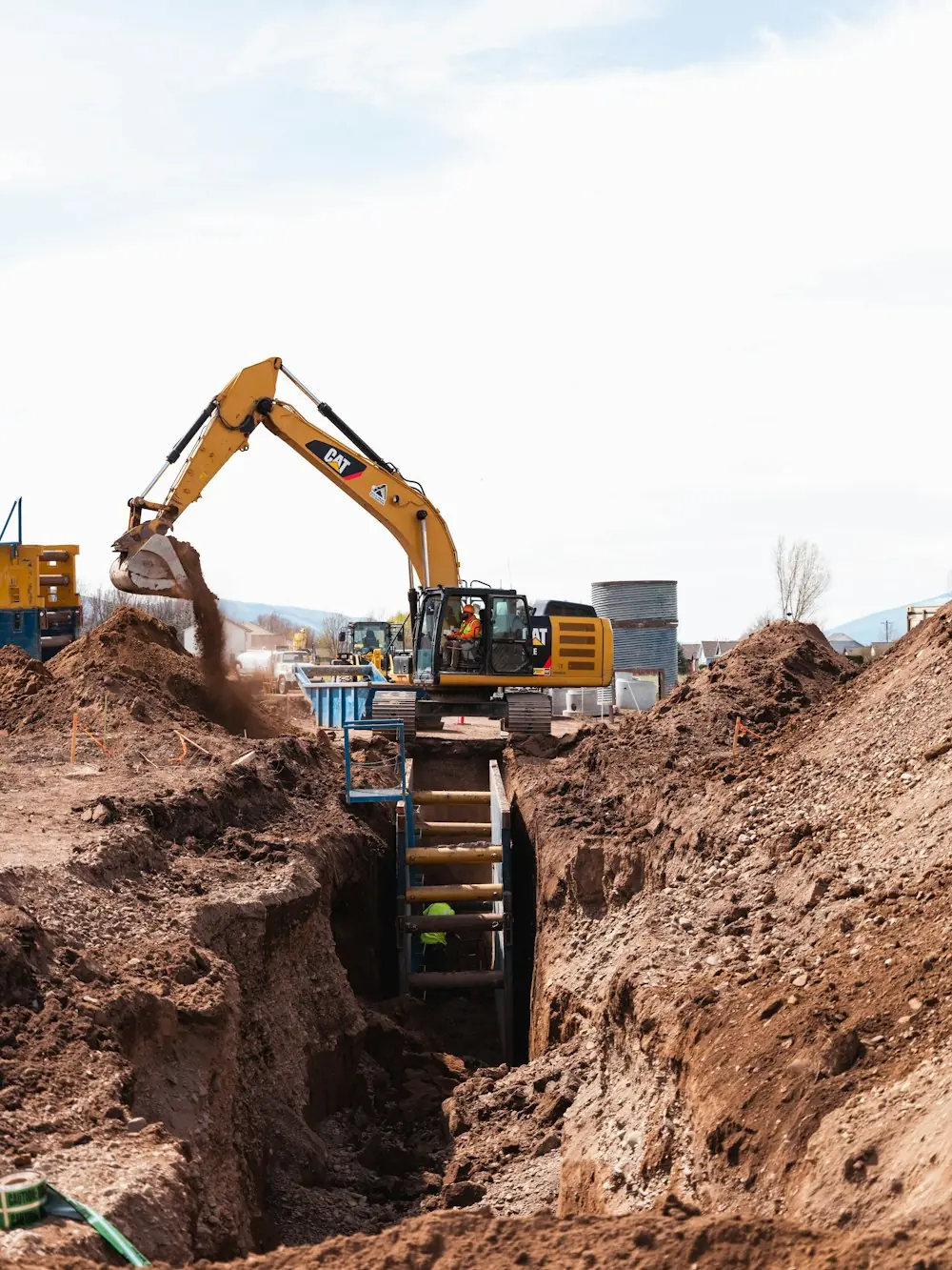 An excavator digging a deep trench on a job site