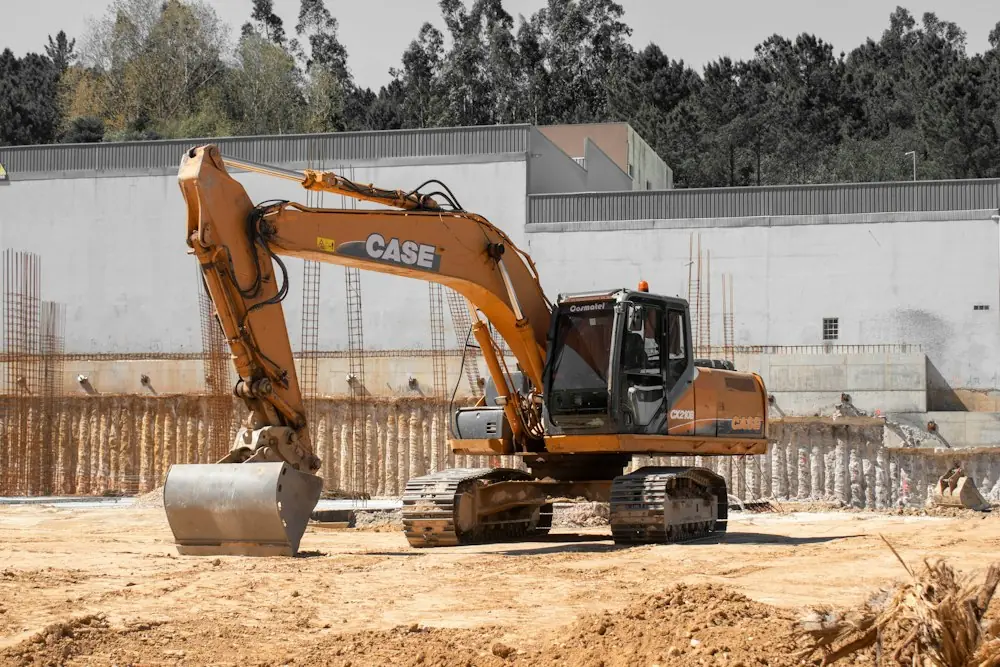 An excavator on a cleared site beside new foundation walls